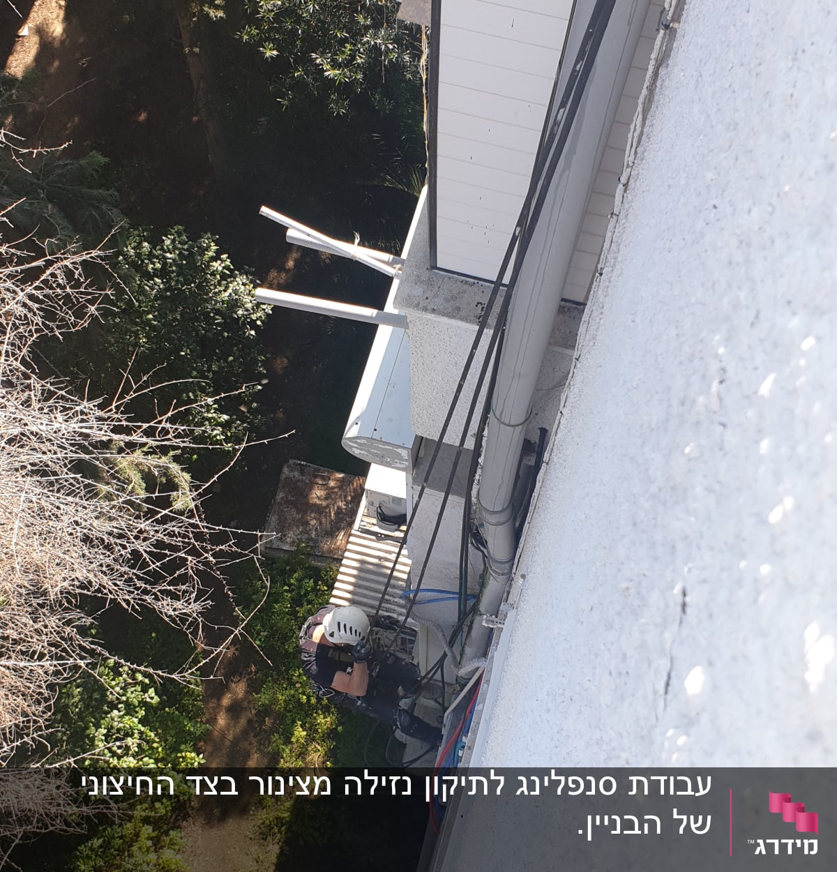 אדם עם קסדה עובד על קיר חיצוני של בניין